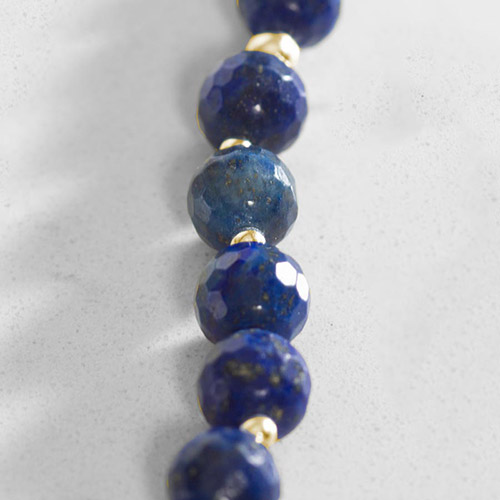 Faceted lapis-colored gemstone beads with natural gold flecks, separated by shiny gold-tone spacers.