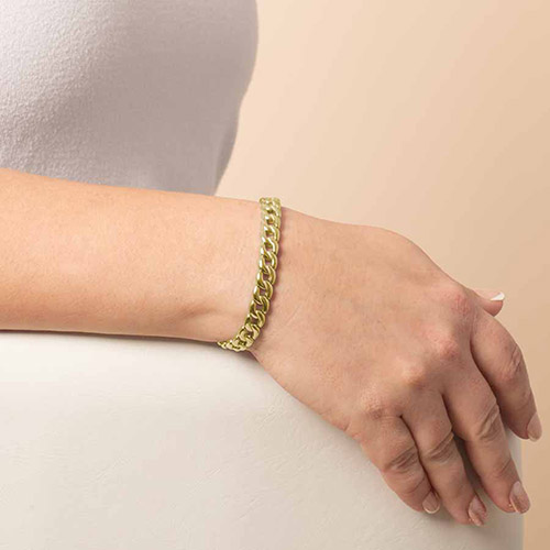 Close-up of a woman's wrist wearing a Lauren’s Hope stretch curb chain medical ID bracelet in polished gold finish, styled with a white sleeveless top.