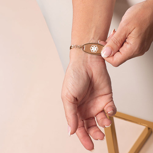 Woman wearing gold medical ID bracelet with black band, showing engraved medical information on wrist – ideal for diabetes, insulin pump, and emergency contact visibility.