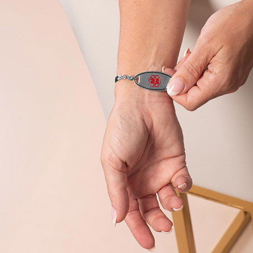 Waverly silver medical ID bracelet for women with red medical symbol on front, photographed on wrist with soft blush background.