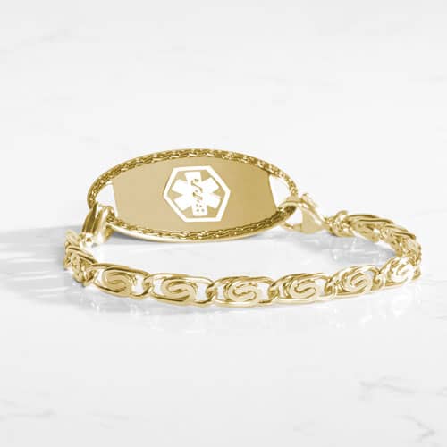 Gold medical ID bracelet with decorative swirl links and engraved medical emblem, combining elegant jewelry style with safety.