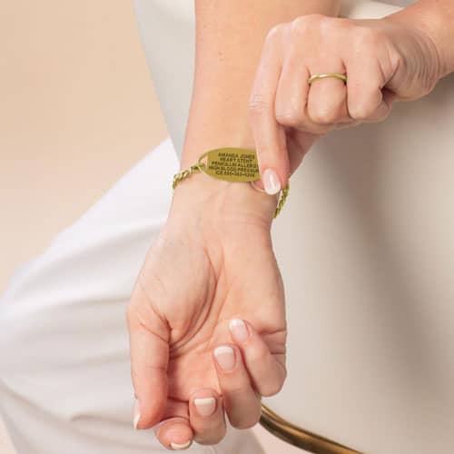Close-up of engraved gold medical ID bracelet displaying health conditions and emergency contact details for everyday safety.