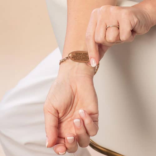 Close-up of engraved rose gold medical ID bracelet displaying health conditions and emergency contact information for safety.