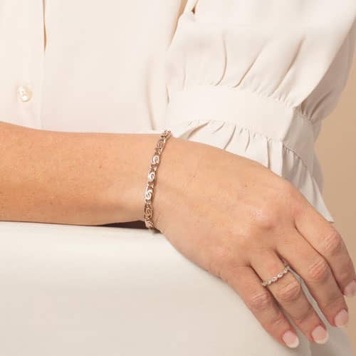 Woman wearing a rose gold bracelet with decorative swirl links, styled as an elegant medical ID bracelet for everyday safety.