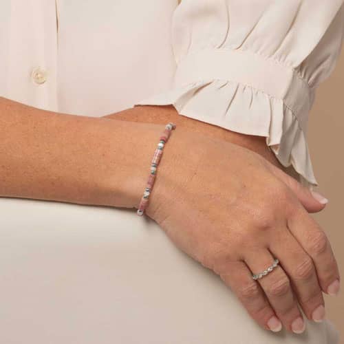 Woman displaying a Beaded bracelet featuring Silver tone and Heishi beads in cream and rose on a stretch bracelet. 