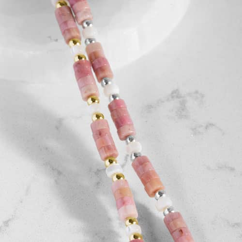Close up of Beaded bracelet featuring Gold  and silver tone, Heishi beads in cream and rose on a stretch bracelet