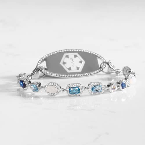 Rhodium and palladium plated medical ID bracelet with sapphire, topaz, aquamarine, quartz, and opal accents paired with silver tone medical ID tag with a border of CZ stones.