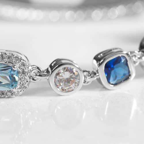 Close up of a Rhodium and palladium plated medical ID bracelet with sapphire, topaz, aquamarine, quartz, and opal accents.