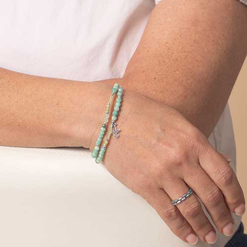 Woman wearing a beaded mint green and silver medical ID bracelet.