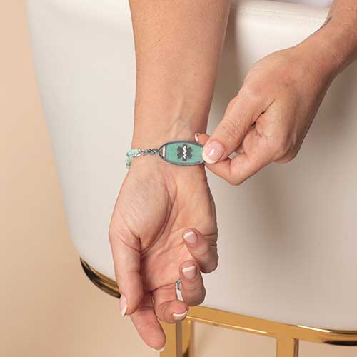 Woman Displaying a silver tone medical ID tag, featuring inlaid Amazonite with a silver medial alert symbol.