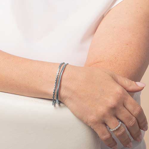 Silver chain medical alert bracelet styled on wrist, layered look showing everyday wear and fit.