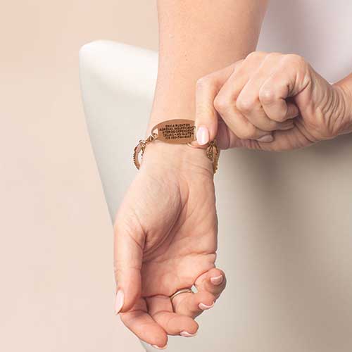 Woman wearing rose gold medical ID bracelet showing engraved emergency information on underside for discreet safety.