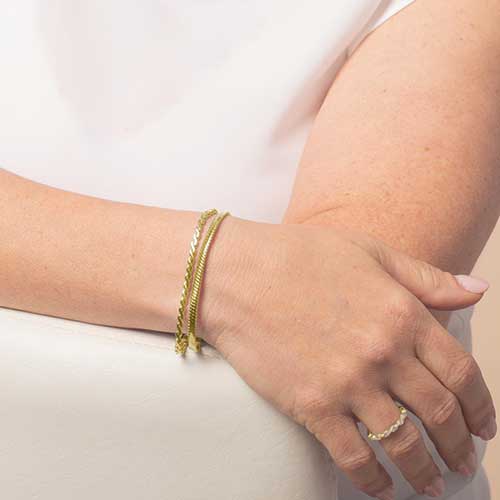 Gold medical alert bracelet styled on wrist with layered chain design for everyday wear.