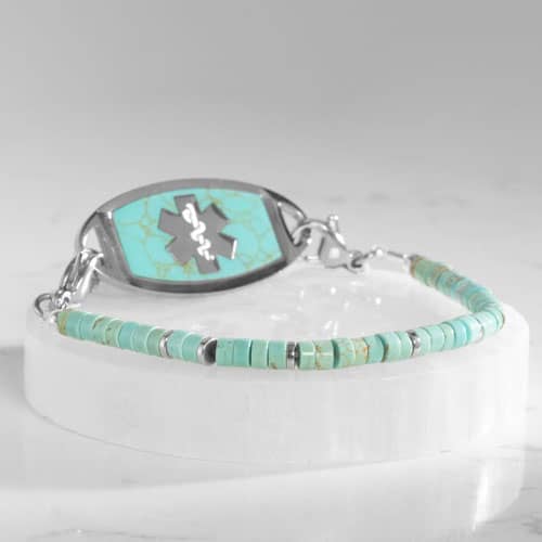 Silver-tone medical ID bracelet with turquoise stone inlay ID tag, turquoise heishi beads, and silver spacer accents on a white display.