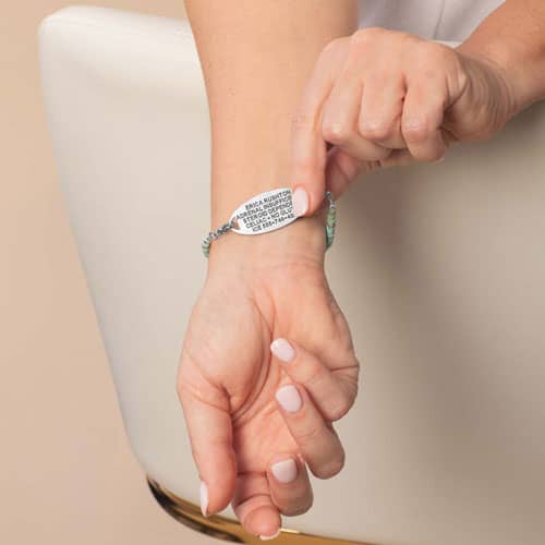 Model lifts the oval medical ID tag to display the engraved medical information on the back of the bracelet.