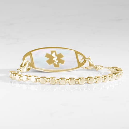 Facet Gold interchangeable bracelet paired with a gold-tone medical ID tag featuring a white mother-of-pearl inlay and medical alert symbol.