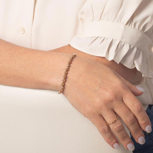 Woman wearing the Facet Rose interchangeable bracelet featuring polished rose gold-tone faceted links with a modern, elegant look.