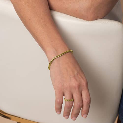 Woman wearing the Faron Gold interchangeable bracelet featuring polished gold-tone curb links with a coordinating matching ring.