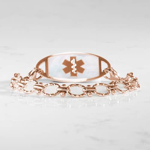 Rose gold medical ID bracelet featuring an ornate filigree-style alert tag with the Star of Life symbol and interchangeable design.