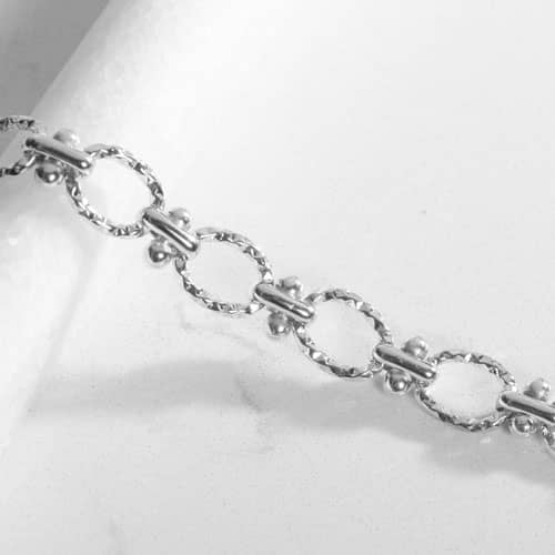 Close-up of the Iris bracelet's textured oval links and bead accents, highlighting the polished silver-tone finish and craftsmanship.