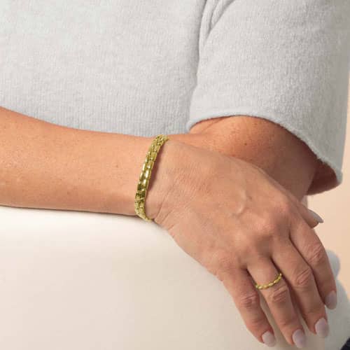 Model wears a gold-tone medical ID bracelet with a double-row rectangular link design and oval ID tag.