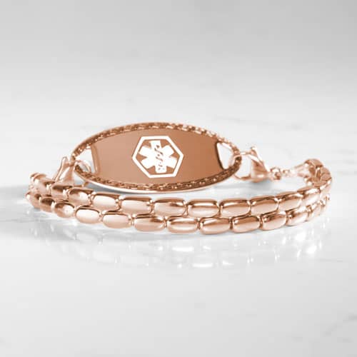 Rose gold-tone medical ID bracelet with a double-row rectangular link design and oval ID tag displayed on a marble surface.