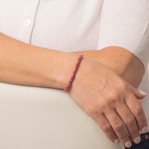 Pink heishi bead medical ID bracelet worn as a slim, minimalist beaded bracelet on the wrist.