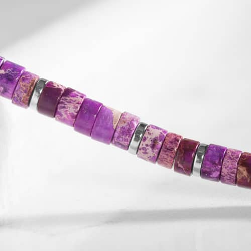 Close-up of purple heishi beads with natural stone patterning and polished silver spacer accents.