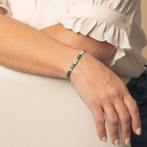 Model is wearing a slim olive green, white, and silver-tone medical ID bracelet with rectangular accents and a minimalist design.
