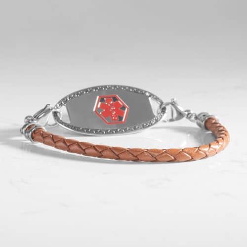 Angled view of a brown braided bracelet with a silver-tone medical ID tag and red medical symbol.