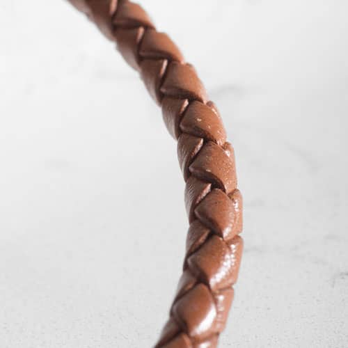 Close-up of the brown braided bracelet, highlighting its woven texture and smooth finish.