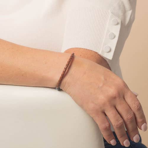 Model is wearing a slim brown braided bracelet, showing the bracelet design from the top of the wrist.