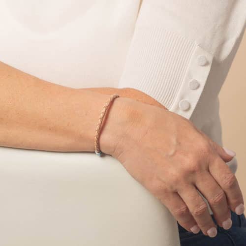 Model is wearing a slim light tan braided bracelet, showing the bracelet design from the top of the wrist.