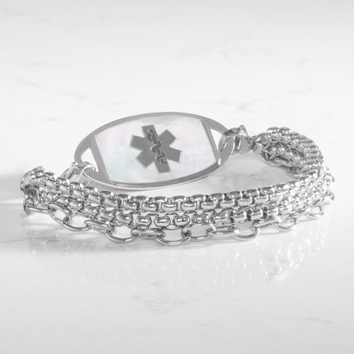 Silver-tone layered medical ID bracelet with mixed chain textures and an oval mother-of-pearl ID tag displayed on a marble surface.
