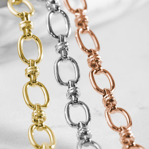 Close-up of oval-link bracelet chains in gold, silver, and rose gold tones.