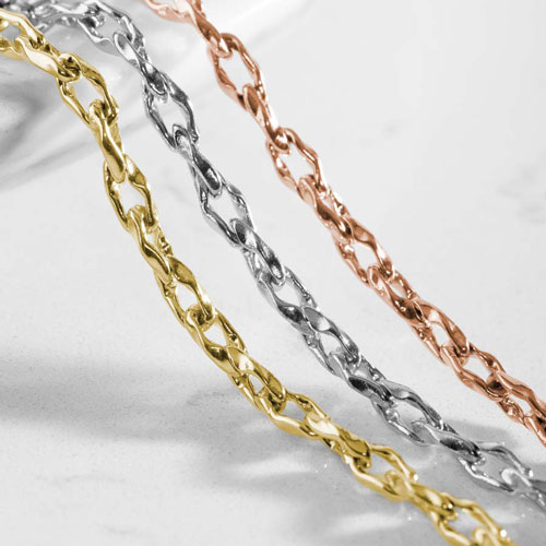 Close-up of interlocking chain bracelets in gold, silver, and rose gold tones displayed side by side.