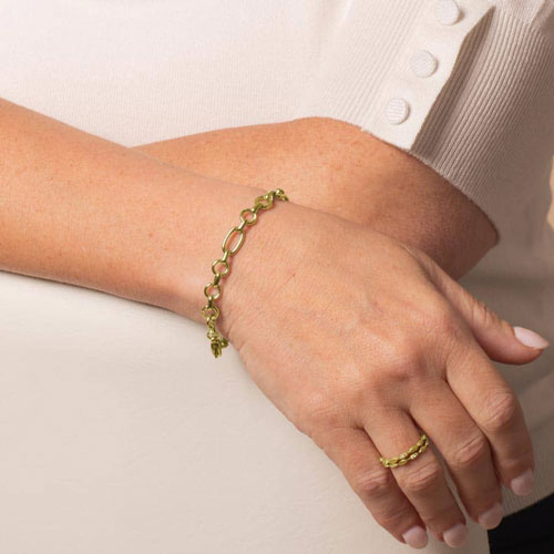 Model is wearing a gold-tone Langley bracelet featuring alternating oval and round links with a lobster clasp.