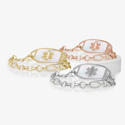 Three Langley medical ID bracelets in gold, rose gold, and silver tones with oval links and iridescent Star of Life ID tags.