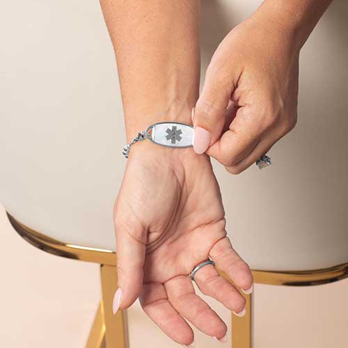 Model is wearing a silver-tone medical ID bracelet with a mother-of-pearl inlay tag featuring the Star of Life symbol.