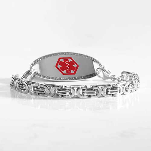 Silver-tone medical ID bracelet with geometric link design and red medical symbol, displayed on a reflective surface.