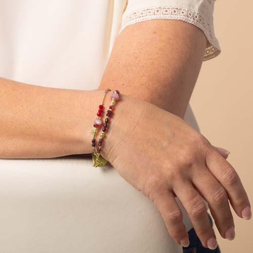 Woman wearing ruby, garnet, and pink crystal and beaded multi-strand medical ID bracelet.