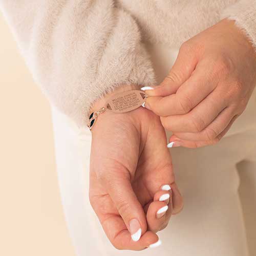 Woman wearing rose gold tone stainless steel medical ID tag with premium laser engraving.