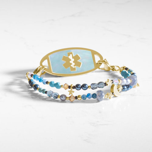 Gold-tone medical ID bracelet with a blue mother-of-pearl emblem plate, layered gemstone strands, and celestial moon and star charms.