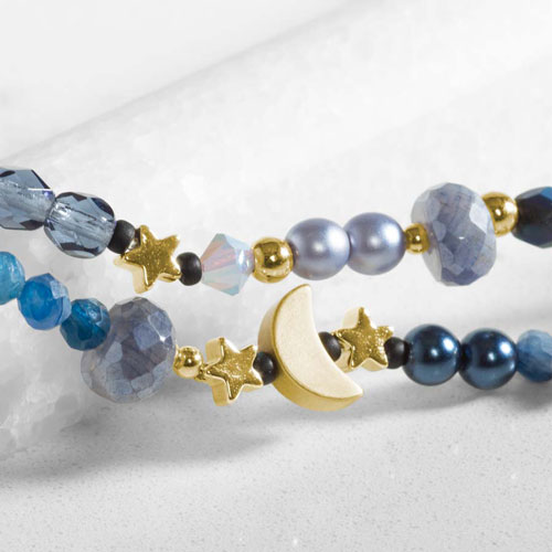 Close-up of a celestial-inspired medical ID bracelet strand featuring blue gemstones, pearl accents, gold moon and star charms.