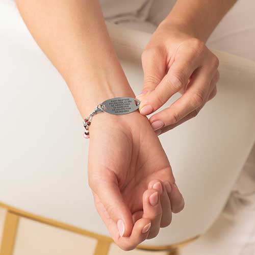 Woman showing custom laser engraved Oval Filigree medical ID tag