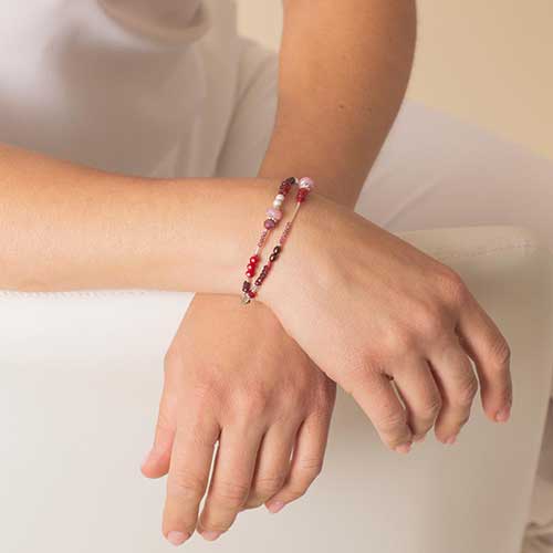 Woman with hands crossed wearing red and pink beaded medical ID bracelet