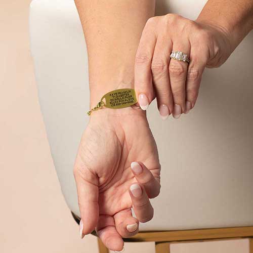 Model wearing dual-tone beaded medical ID bracelet with engraved tag facing outward.