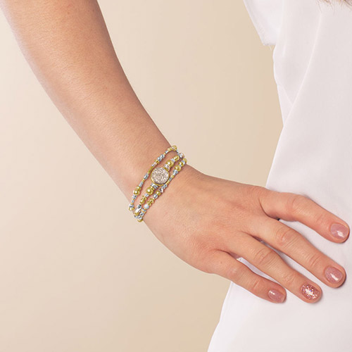 Front view of model wearing two-strand gold and silver medical ID bracelet with beaded detail.