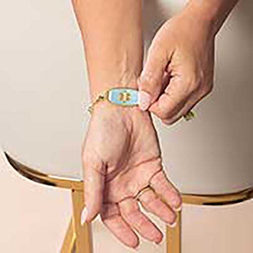 Model wearing the Rhythm & Blues in Gold bracelet with the medical emblem side of the tag facing outward.