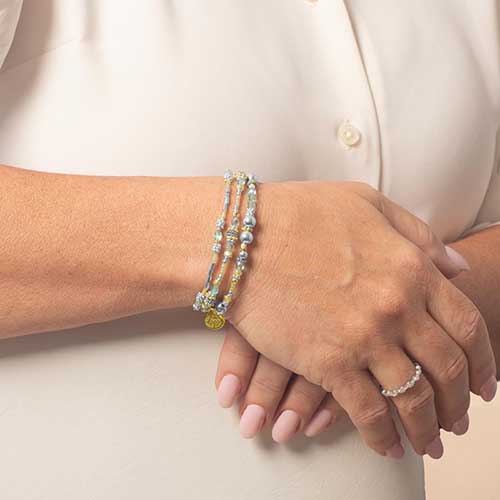Model wearing the Rhythm & Blues in Gold bracelet with the engraved side of the tag showing on the wrist.